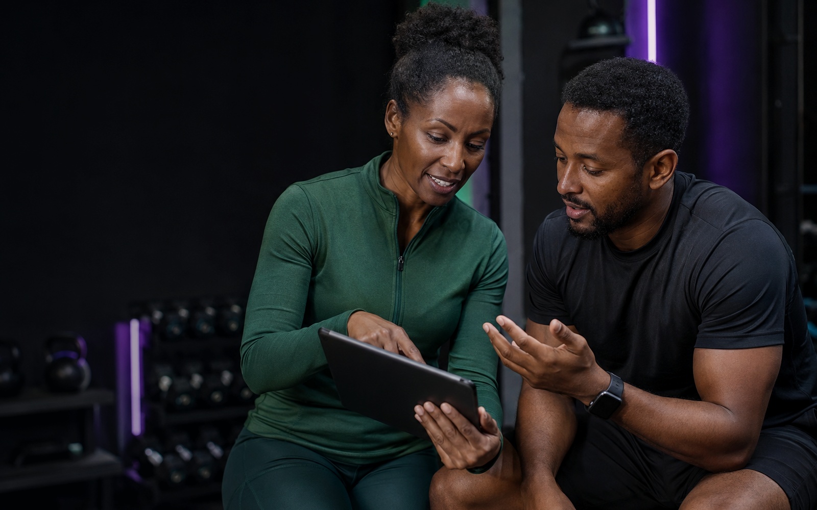 Fitness coach and participant reviewing progress together on a tablet